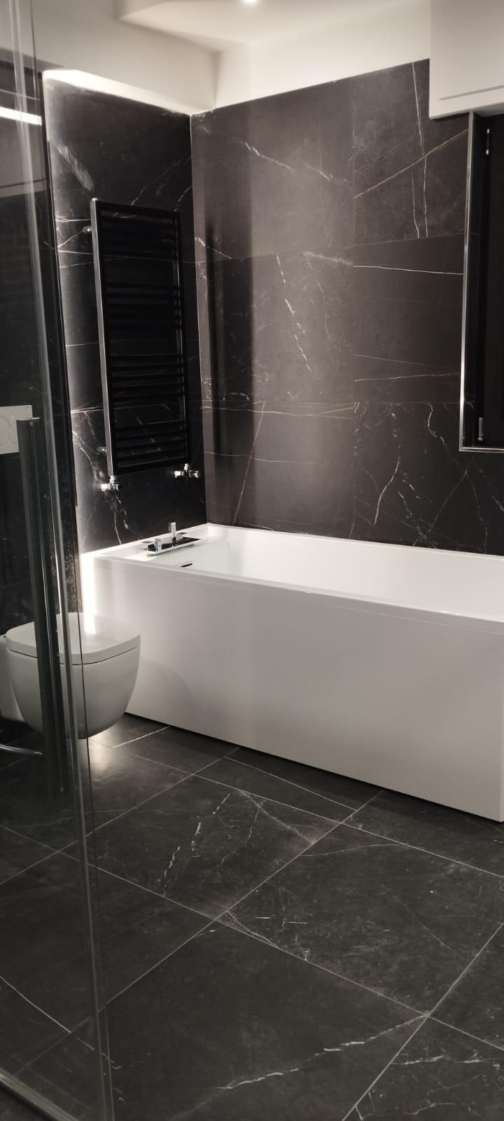 Bagno moderno con rivestimenti scuri e vasca integrata